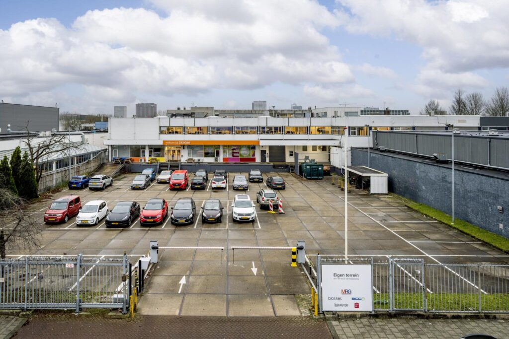 Parkeerterrein met diverse auto's voor het hoofdkantoor van Blokker aan de Van der Madeweg.